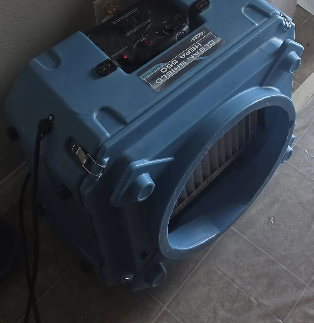A blue air scrubber beside a plastic containment wall