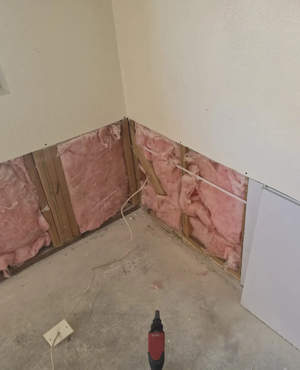 A drywall sheet staged at a wall cut open above the floor