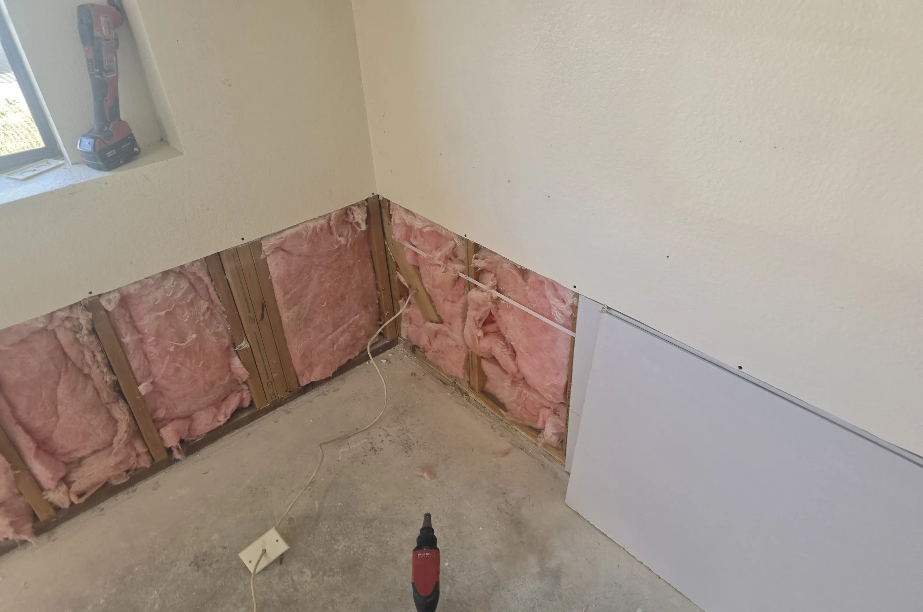 A drywall sheet staged at a wall cut open above the floor