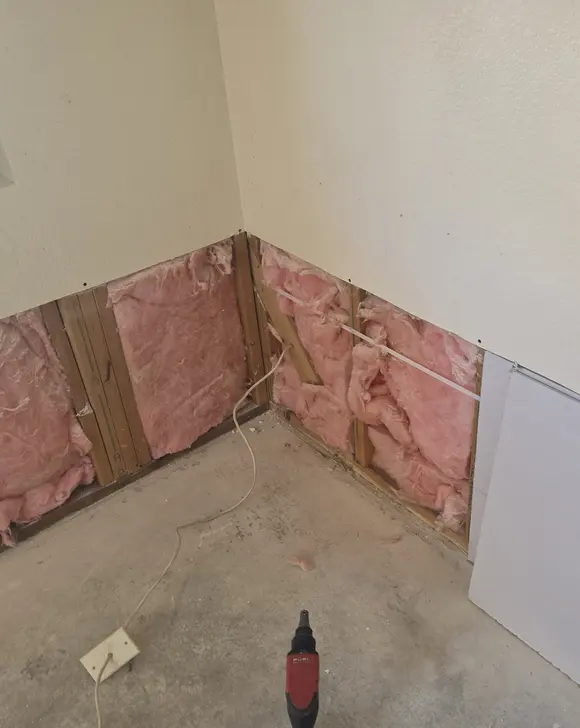 A drywall sheet staged at a wall cut open above the floor