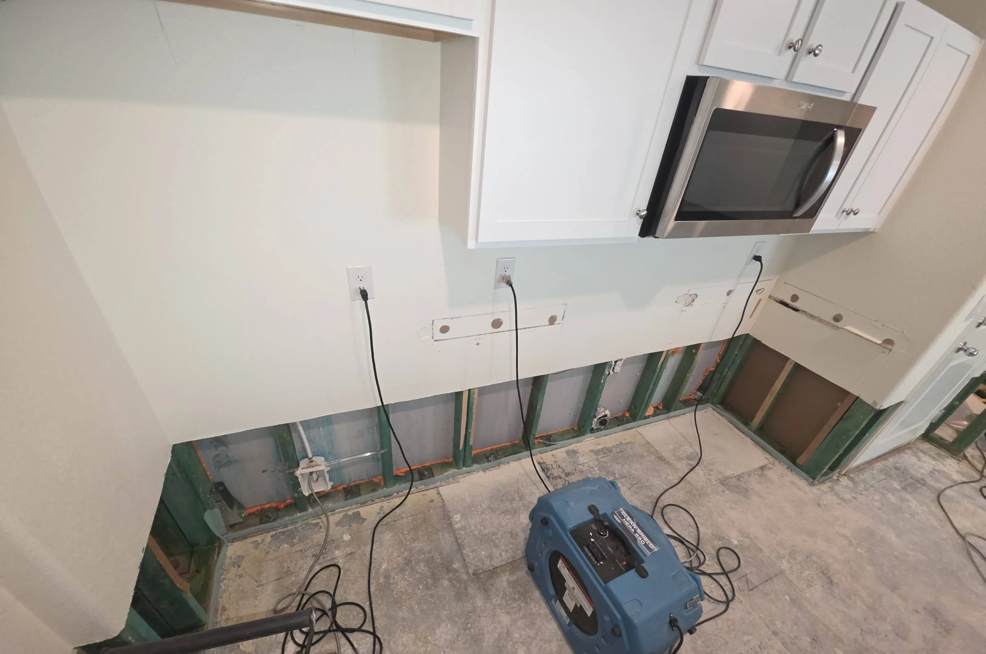 A kitchen with the lower wall cut out and a blue air scrubber on the floor