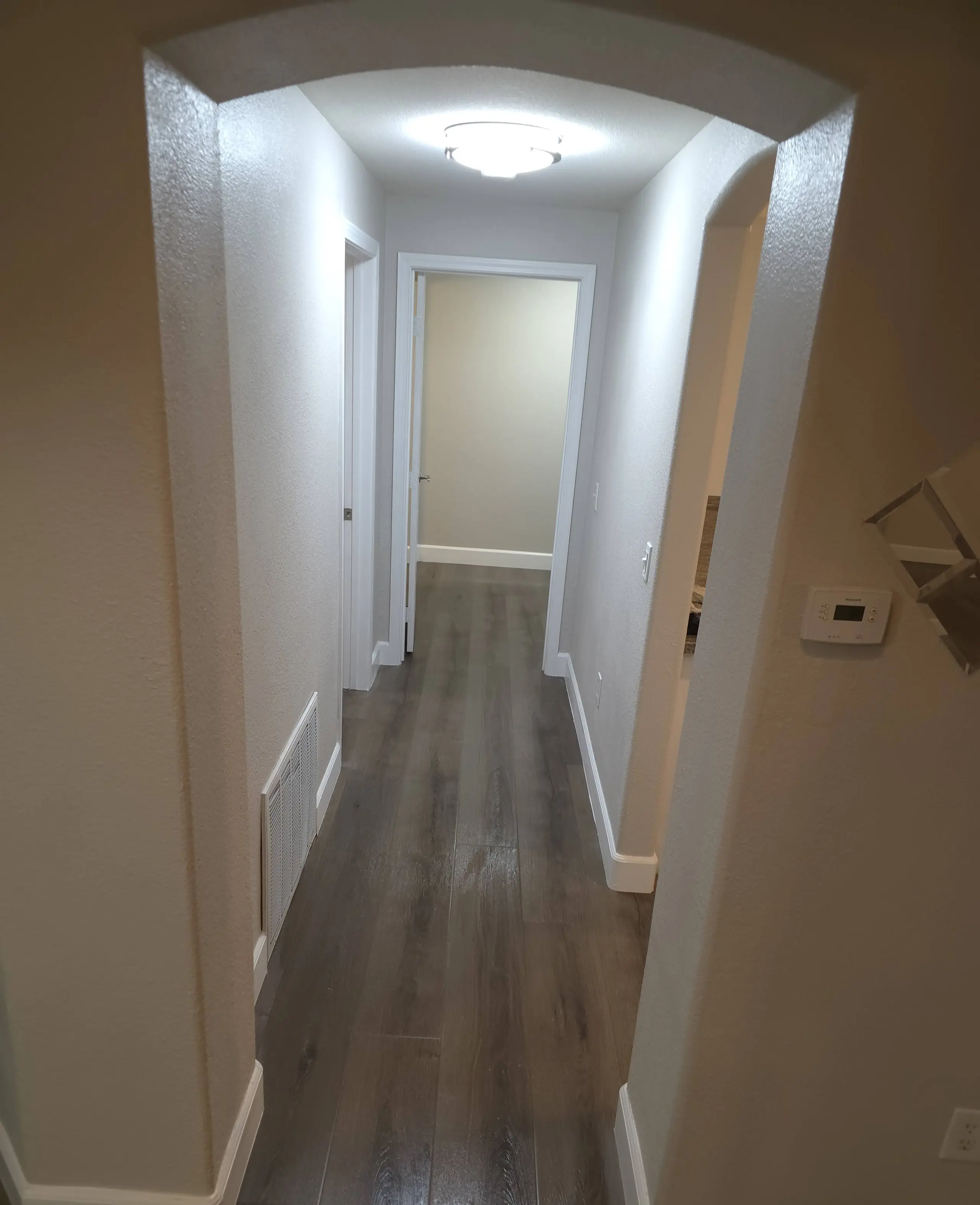 The same hallway after the rebuild, with new drywall, baseboards, paint and a dark plank floor