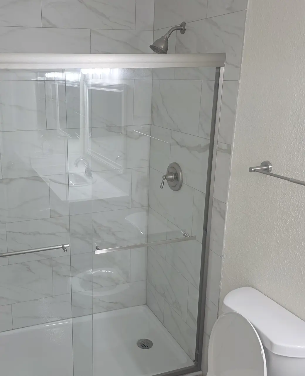 A tiled shower with a sliding glass door