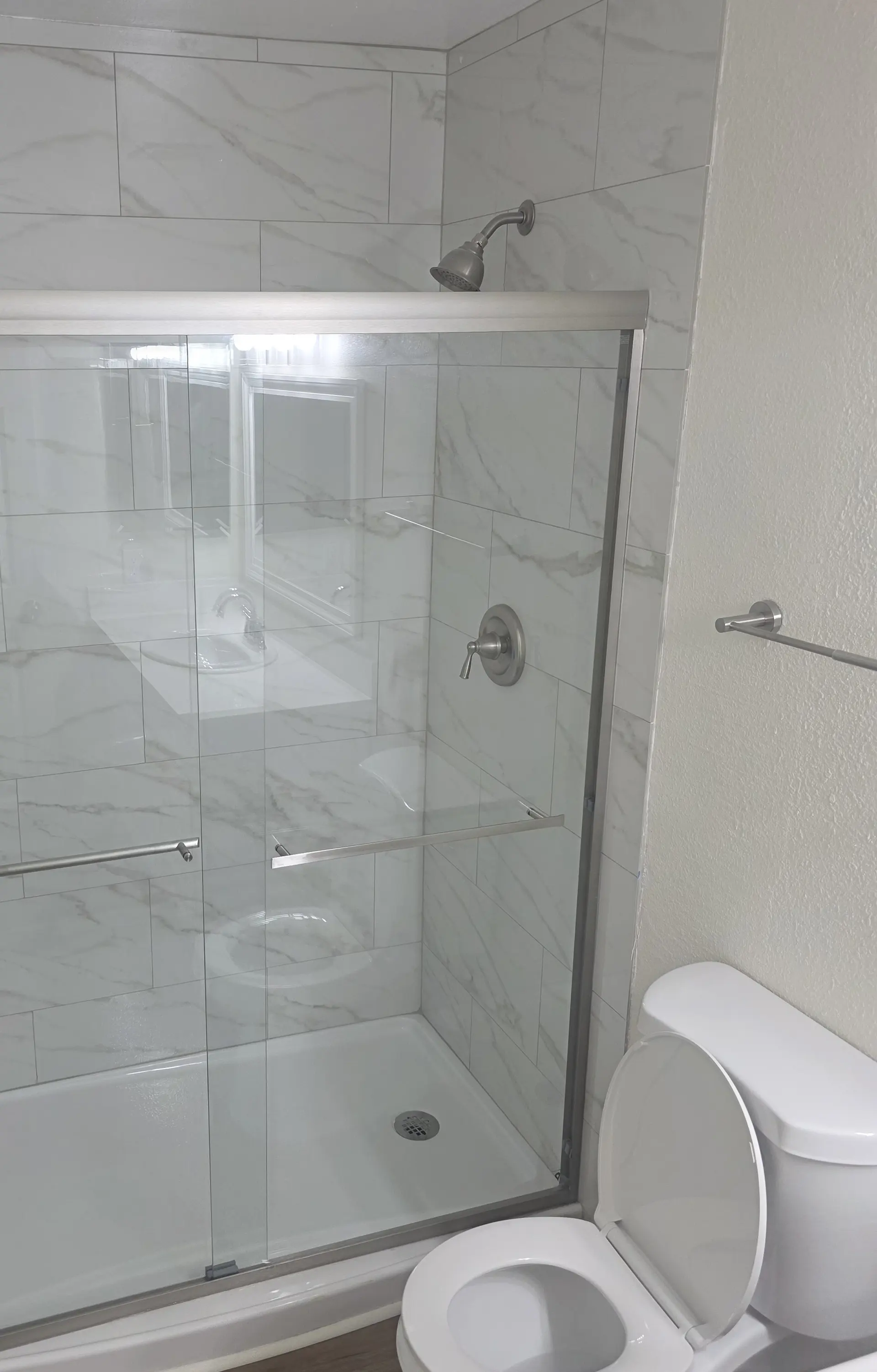 A tiled shower with a sliding glass door