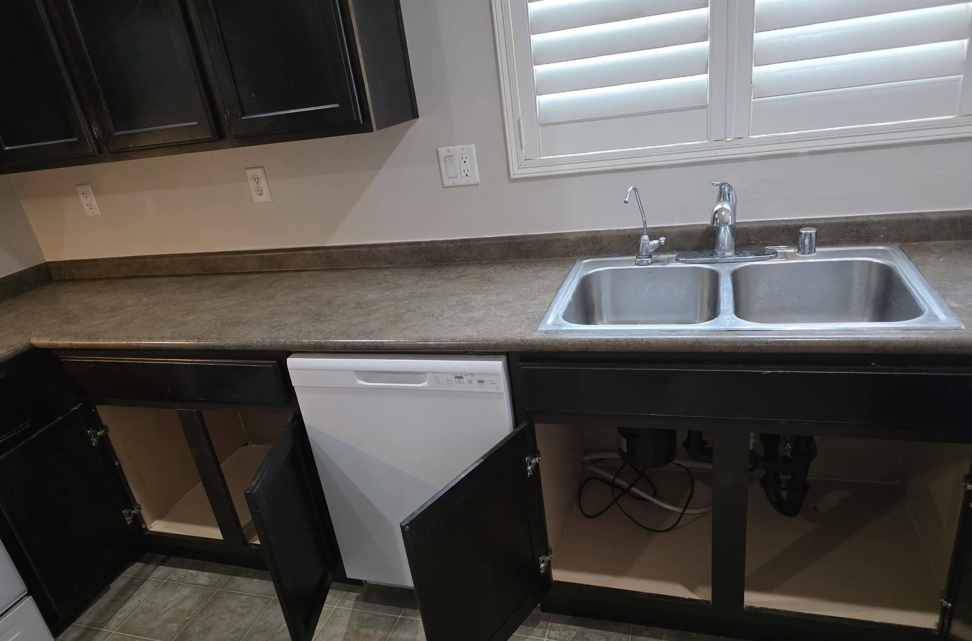 A double-bowl kitchen sink with new dark base cabinets beneath it